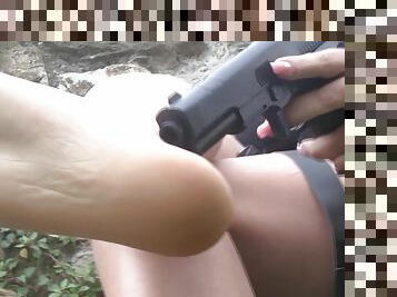 Gun wielding beauty shows off her erotic feet outdoors