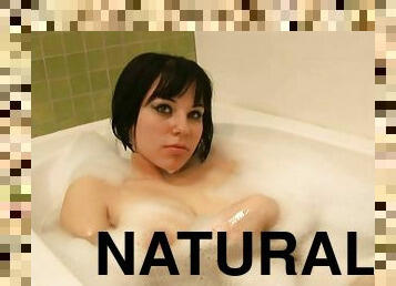 Dark haired girl lowers her curvy body into a warm bubble bath