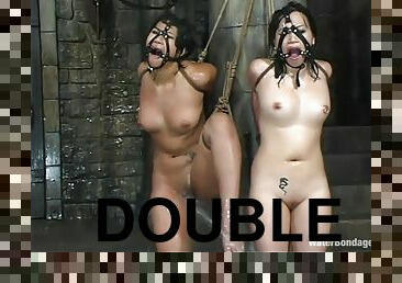 Two hot brunettes share a double dildo in hot BDSM scene