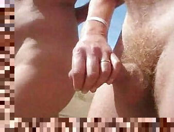 Chubby chick pleases some guy with a handjob on a beach