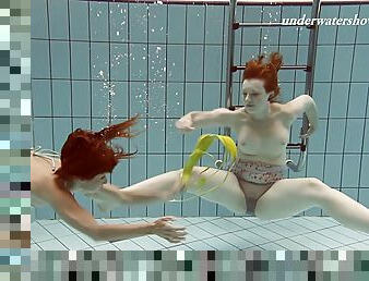 Two hot redhead cuties strip down inside of the pool