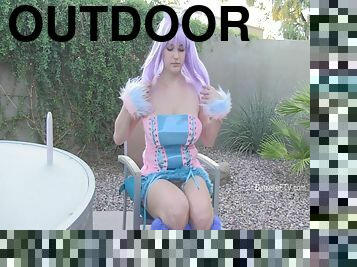 A curvy girl in a doll outfit toys her juicy vagina outdoors