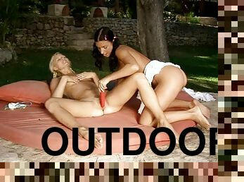 Blonde and brunette chicks toy each other outdoors