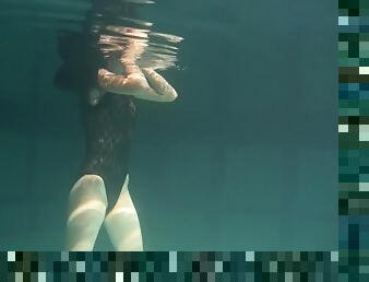 Slim raven-haired cutie undresses while diving inside of a pool