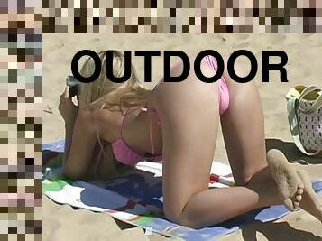 Amazing blonde girl in pink bikini sunbathes on a beach