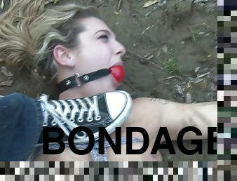 BDSM slut tied up in the dirt and gagged as part of fetish games