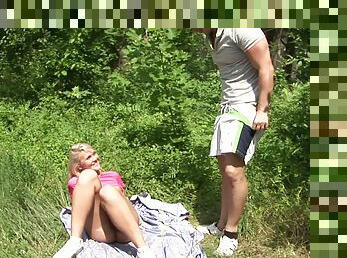 A couple lays a blanket down outdoors, strips and fucks