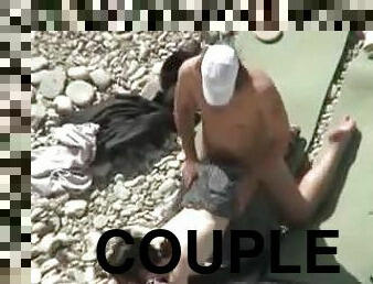 Lewd couple makes love on a nude beach in the presence of their friends