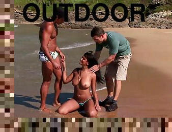 Two guys drill brunette Babalu's pussy on the beach