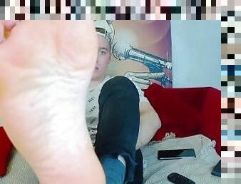 A YOUNG GUY TAKES OFF HIS SOCKS AND SMEARS OIL ON HIS FEET, GETTING HIGH ON STREAMING VIDEO. VERY CU