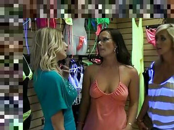 Three beautiful girls make lesbian love in a clothes shop