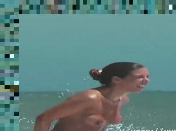 Sexy toned body walking naked on a crowded nudist beach
